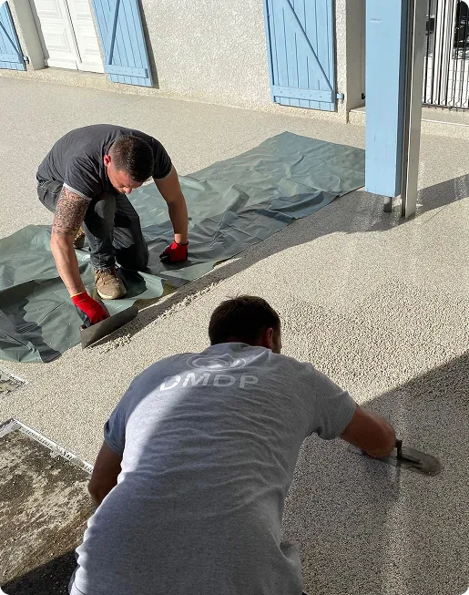 deux artisan entrain de lisser un sol en moquette de pierre sous le porsche d'une maison à Estancarbon près de Saint-Gaudens en Haute-Garonne 31